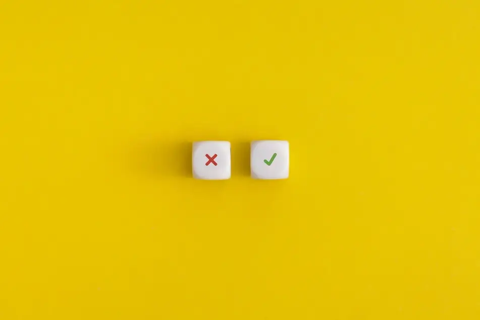 A photograph of two die—one with a red "x" and other with a green checkmark—on a yellow background to represent job search mistakes.