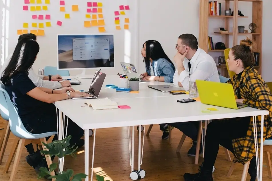 Equipo de personas reunidas alrededor de una mesa de trabajo