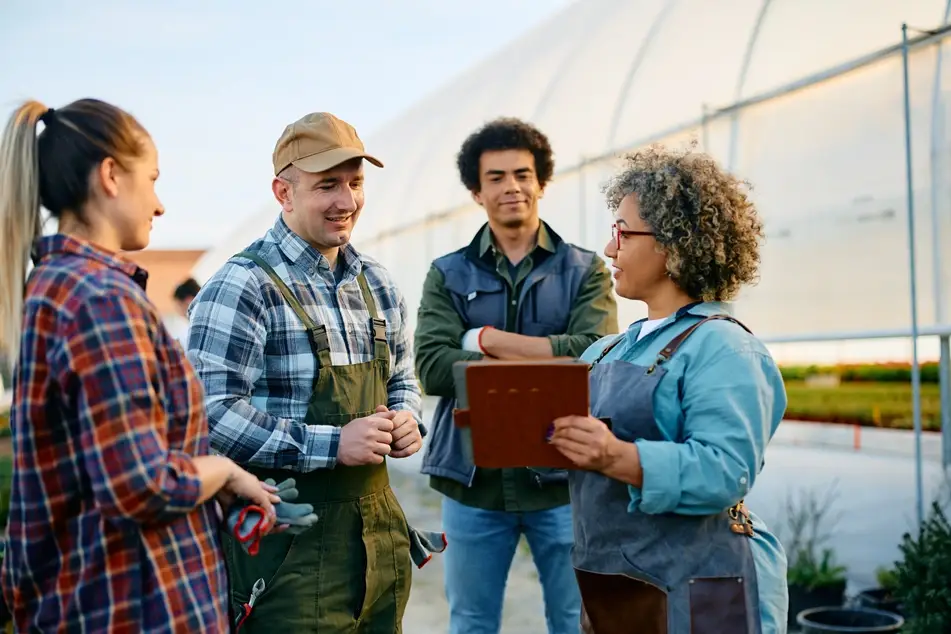 Nonprofit manager at a greenhouse or farm speaks to co-workers to build positive relationships.