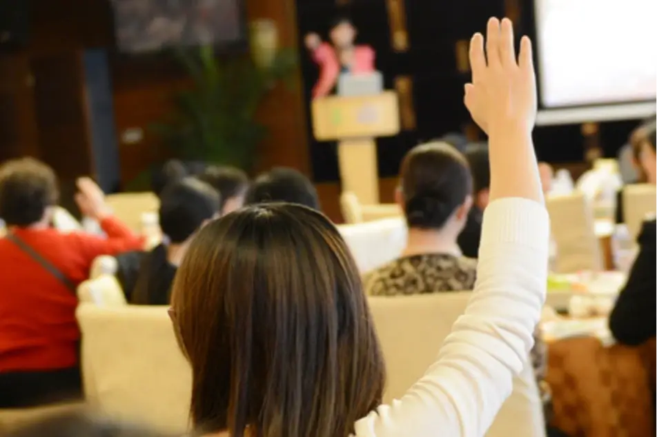Mujer levantando la mano en un curso