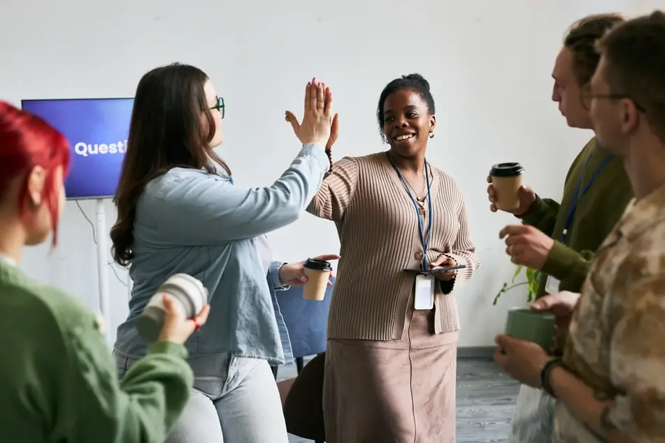 Co-workers with no college degree gathering in office space and high-fiving