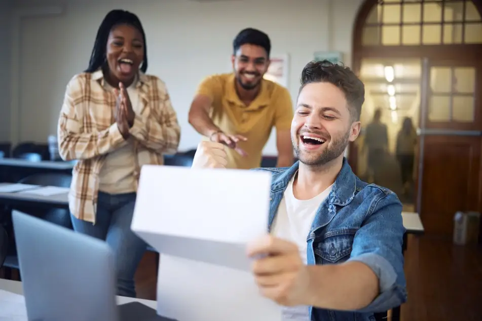 A group of happy students celebrate receiving an offer letter relating to financial aid for graduate school.