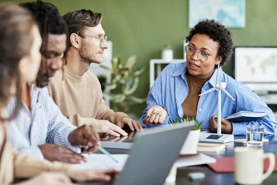 Group of multiracial co-workers gather around a table during a meeting at their new nonprofit job.