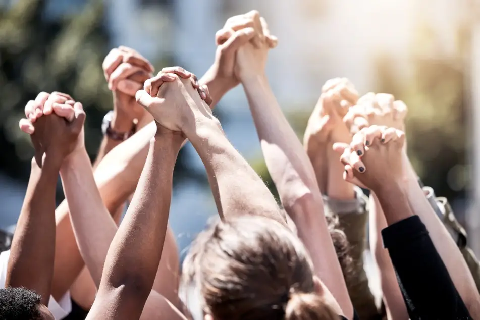 A photograph of multiracial hands grasping each other in the air