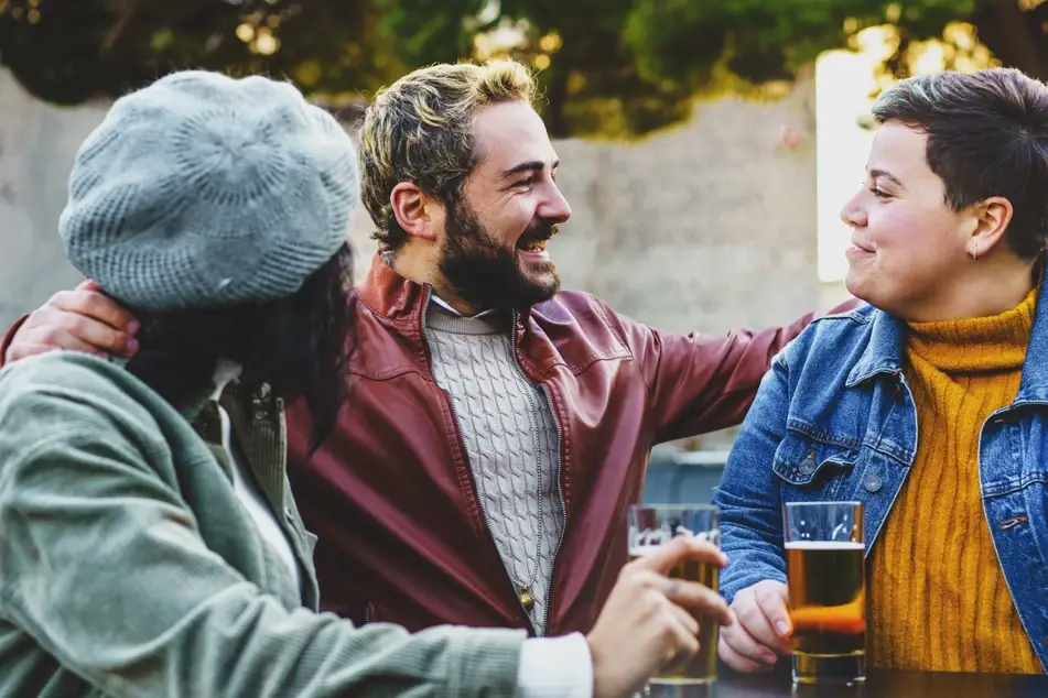 Three friends catching up and drinking beer outside in the fall.