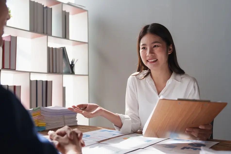 Woman in white blouse interviews someone for a job interview in an office.