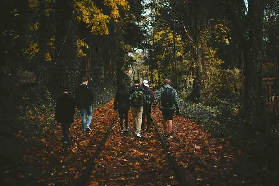 Personas caminando en grupo por las vías del tren.