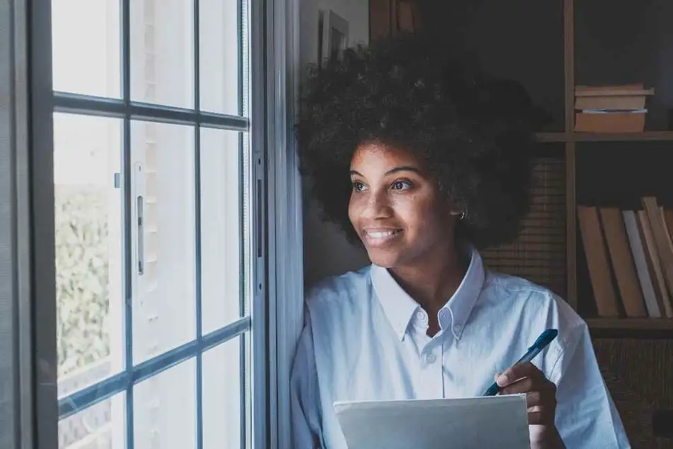 Mujer sonriendo escribiendo sus propósitos de año nuevo