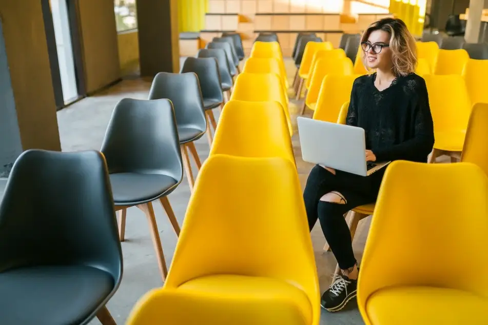 image of blonde woman sitting in university classroom on laptop