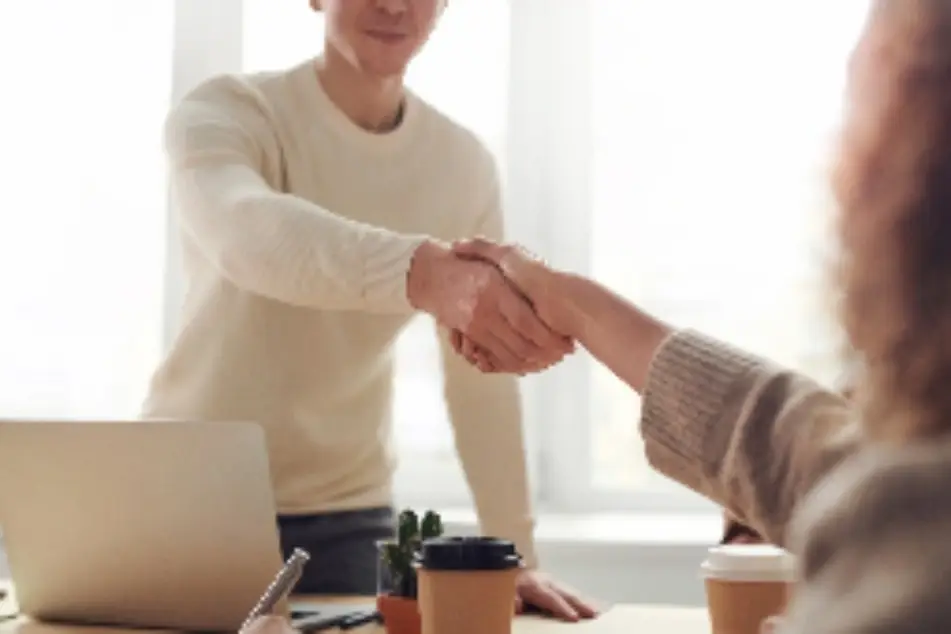 Hombre y mujer se dan la mano de forma cálida y profesional