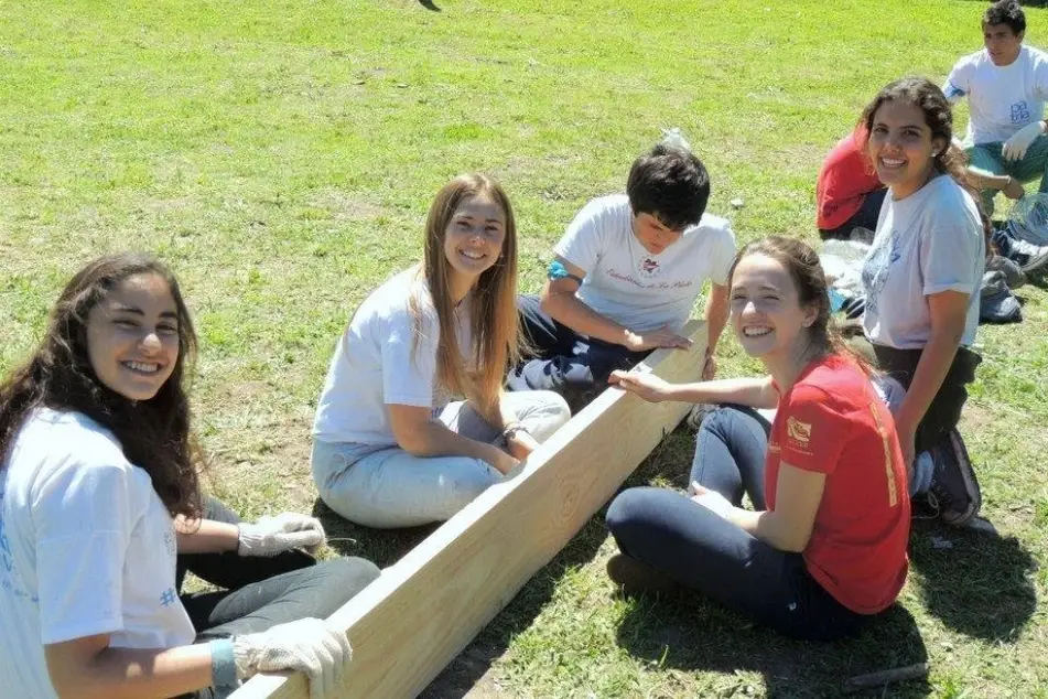 Varias chicas sonrientes miran a cámara mientras trabajan con una viga de madera