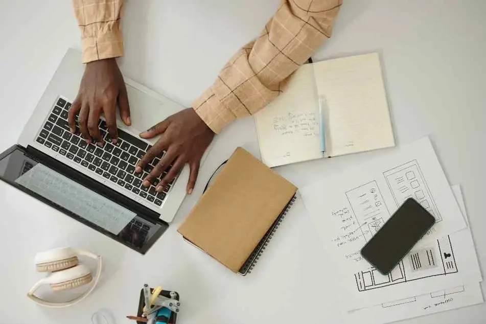 Persona escribiendo en una computadora portátil con notas a su al rededor