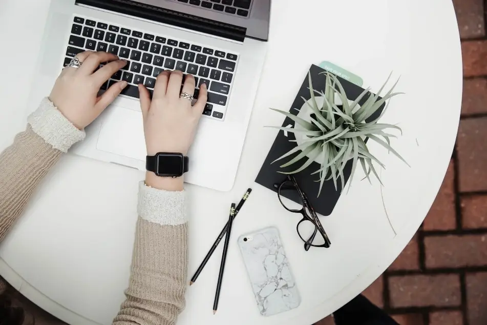 Las manos de una mujer escribiendo en una computadora