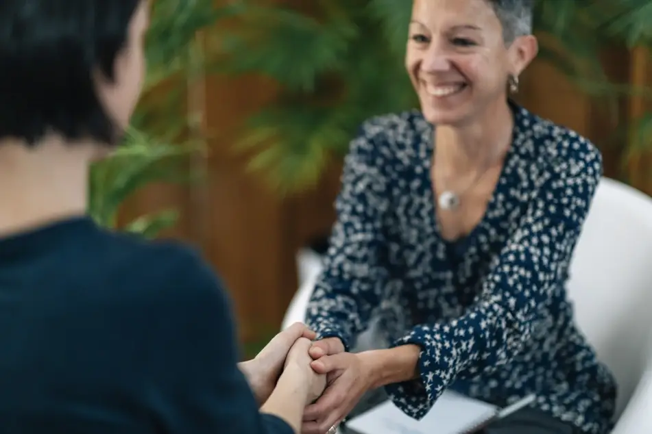 two women work together, one is a life coach and is smiling.