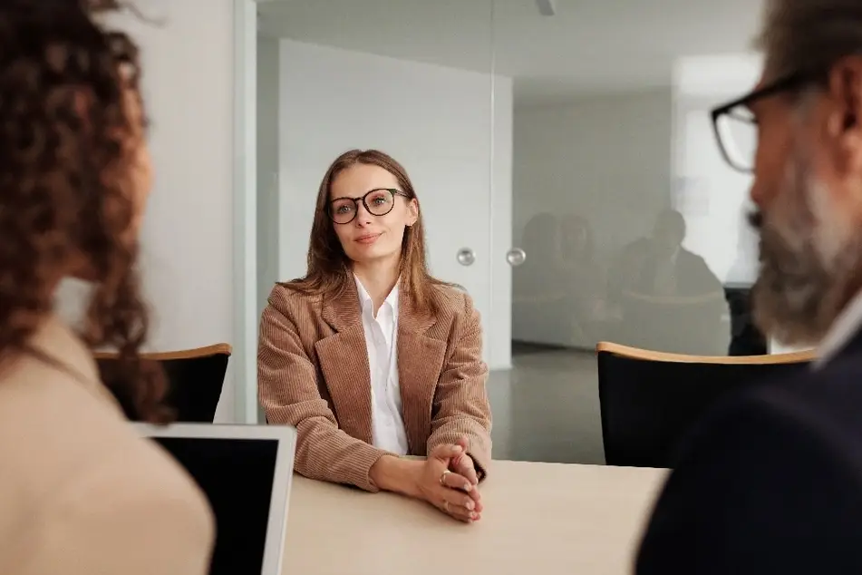 Mujer sentada en una mesa frente a dos entrevistadores