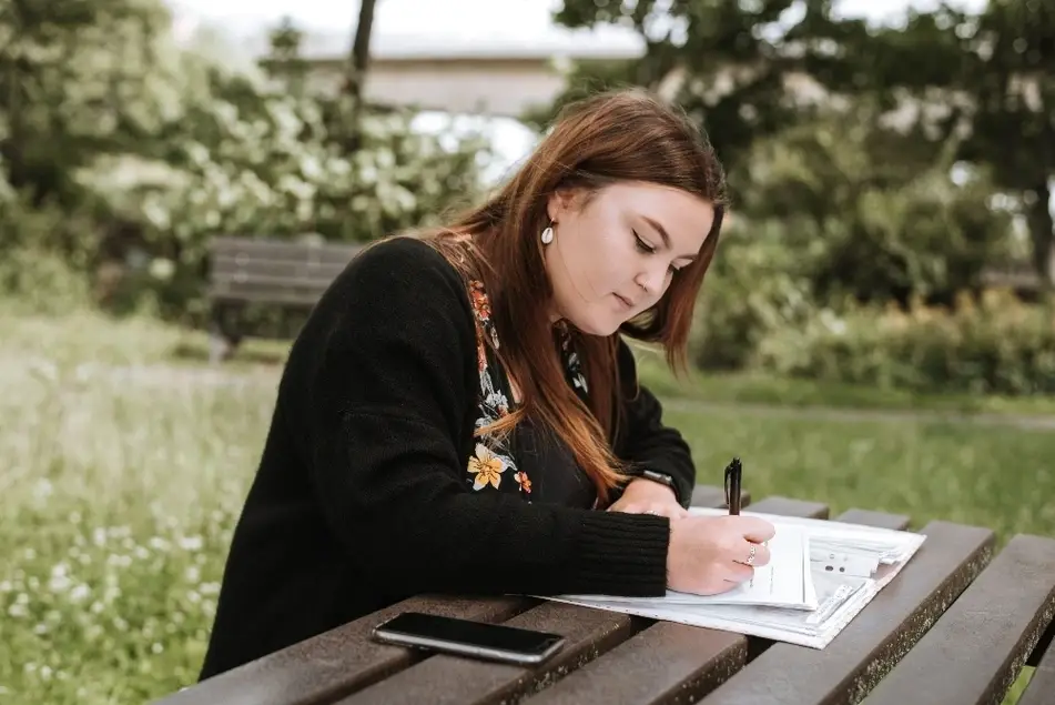 Mujer tomando notas en un parque