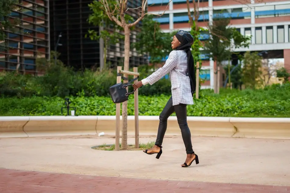 Black woman happily walking outside of her office.