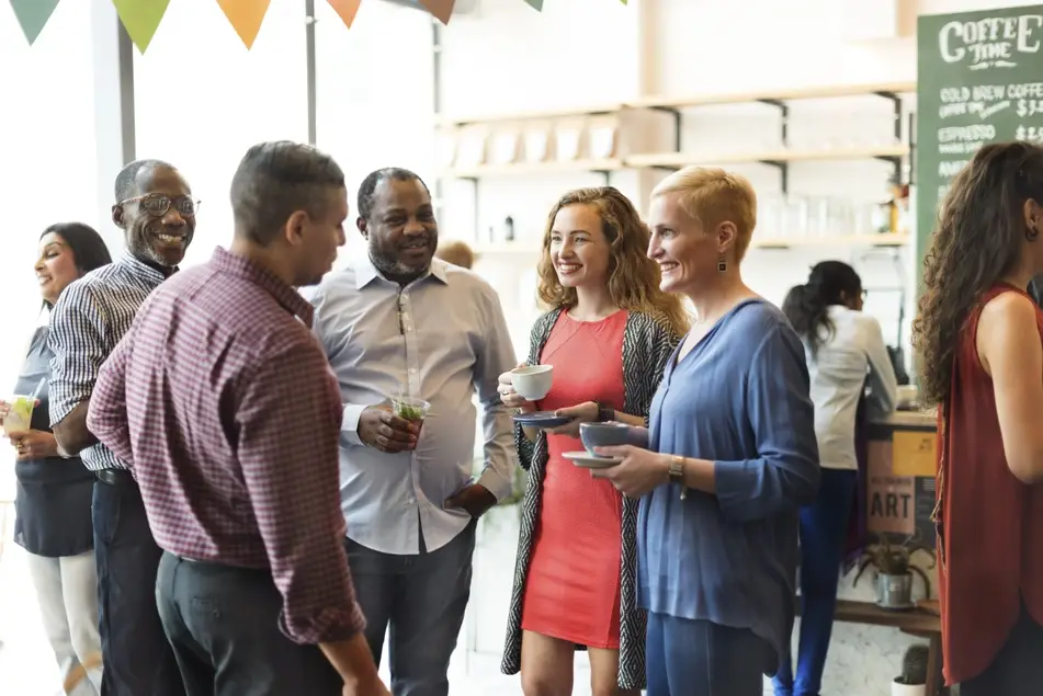 A group of multiracial students and alumni chat at a college party.